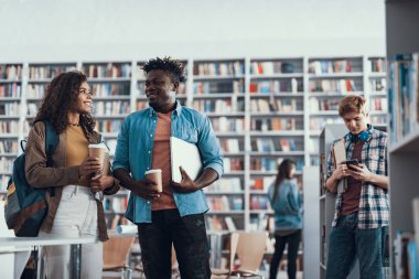 Kahve içme ve konuşmaya gülümseyen iki öğrenci