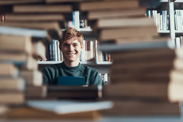 Positiver junger Mann lächelt und blättert in den Büchern — Stockfoto