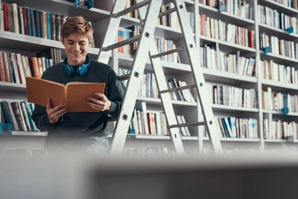 Neugieriger kaukasischer junger Mann liest schönes Buch in der Bibliothek — Stockfoto
