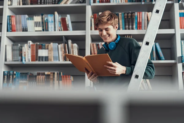 Glücklicher junger Mann lächelt beim Aufschlagen des Buches — Stockfoto