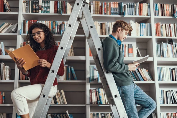 Junger Mann und Frau sitzen auf Leiter und lesen — Stockfoto