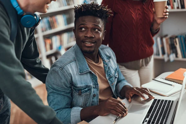 Αφρο-αμερικανικό φοιτητής βλέπει ο φίλος του ενώ κάθεται με το laptop του — Φωτογραφία Αρχείου