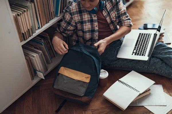 Ruhiger Student, der seinen Rucksack berührt, während er auf dem Boden sitzt — Stockfoto