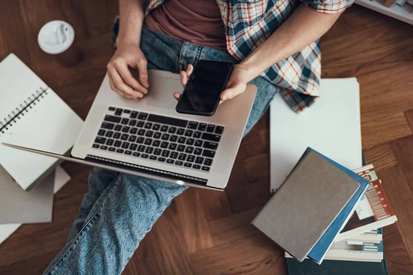 Top view of the person holding laptop and smartphone