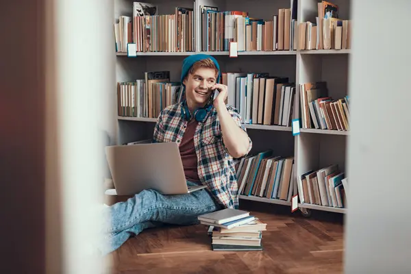 Fröhliche Studentin telefoniert, während sie auf dem Boden sitzt — Stockfoto