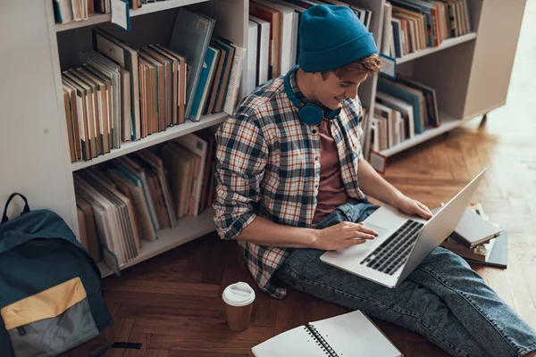 Emotionaler Student sitzt mit Laptop auf den Knien auf dem Boden — Stockfoto