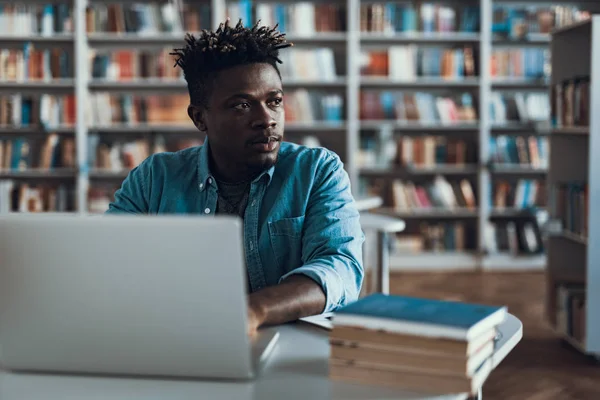 Calma afro-americano olhando para a distância enquanto sentado com laptop — Fotografia de Stock