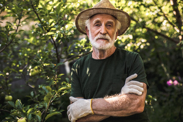 Elderly farmer posing on countryside park background
