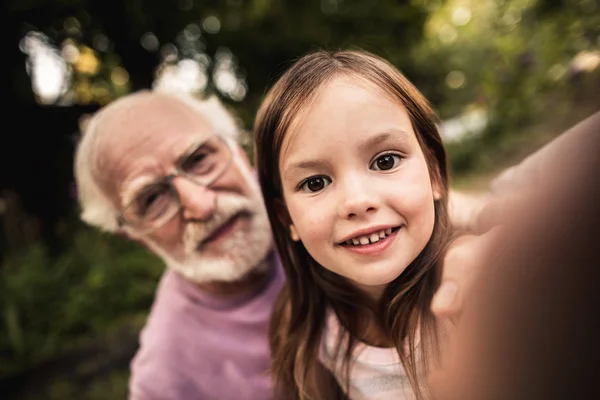 Маленькая девочка делает селфи со своим дедушкой — стоковое фото