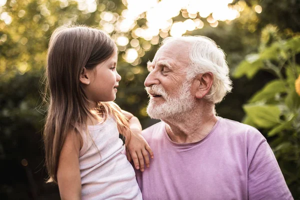 Petite-fille parlant avec son grand-père dans le parc — Photo