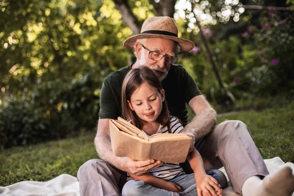 Elderly man learning to read his little granddaughter