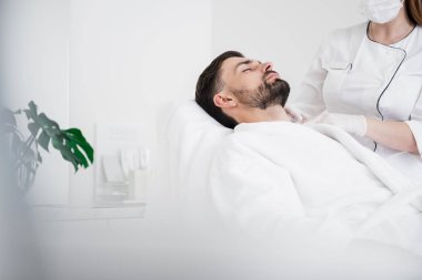 Beyaz bornoz güzellik enjeksiyonları geçiren adam