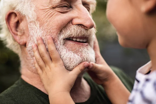 Velho homem sorridente e sua neta olhando um para o outro — Fotografia de Stock