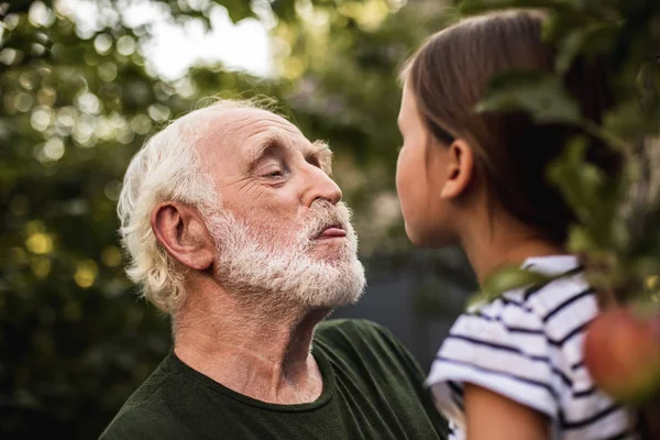 Vieil homme s'amuser avec sa petite-fille dans le verger — Photo