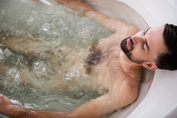 Vista superior del hombre moreno sentado en bañera de hidromasaje — Foto de Stock