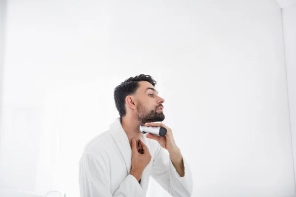 Acercamiento de hombre cuidadoso de pie y afeitándose la barba — Foto de Stock