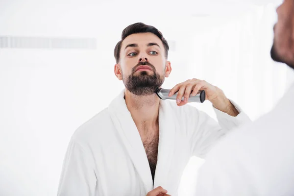 Hombre serio levantando la cabeza mientras se afeita el cuello — Foto de Stock