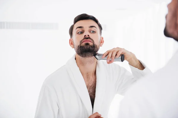 Homem sério colocando a cabeça para cima enquanto raspando o pescoço — Fotografia de Stock