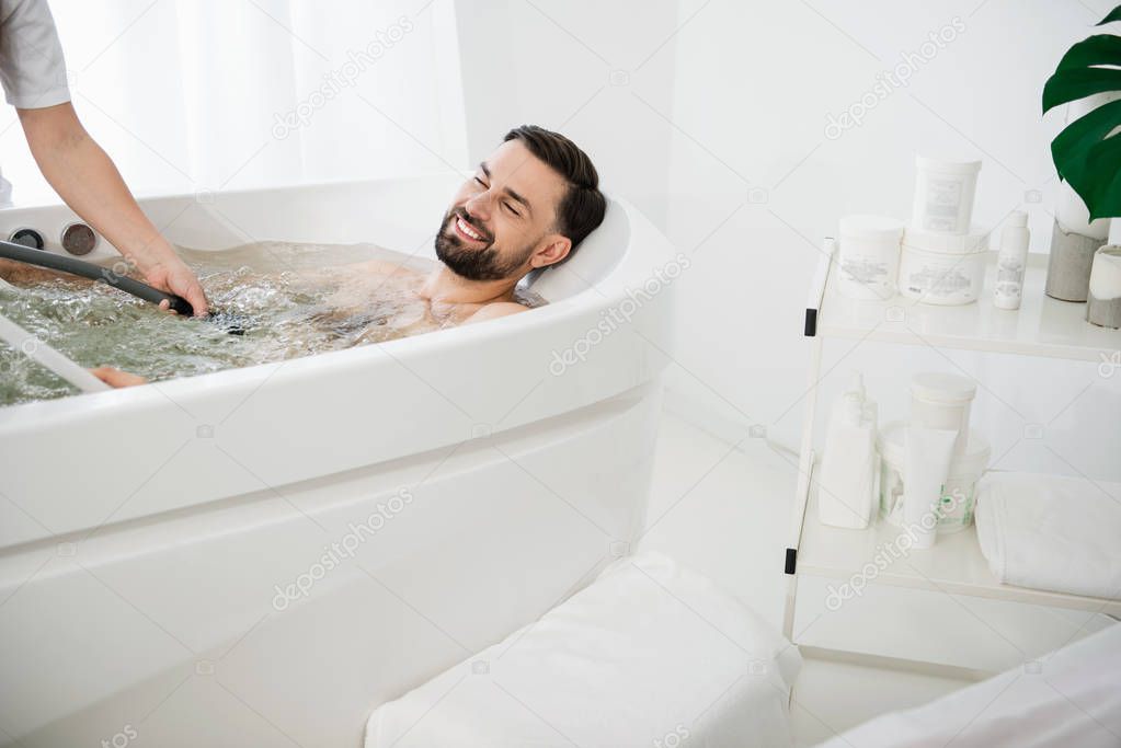Pleased man smiling and enjoying water jets procedure