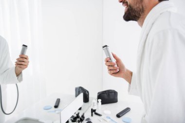 Tıraş makinesi tutan sakallı gülümseyen adam yakın çekim