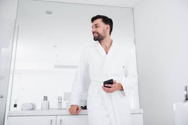 Gülümseyen ve sağa doğru seyir smartphone ile neşeli adam