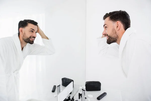 Homem feliz tocando seu cabelo escuro e sorrindo — Fotografia de Stock