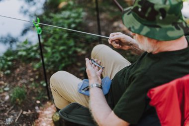 Emekli bir adamın bir yem oltaya koyarak üstten görünüm