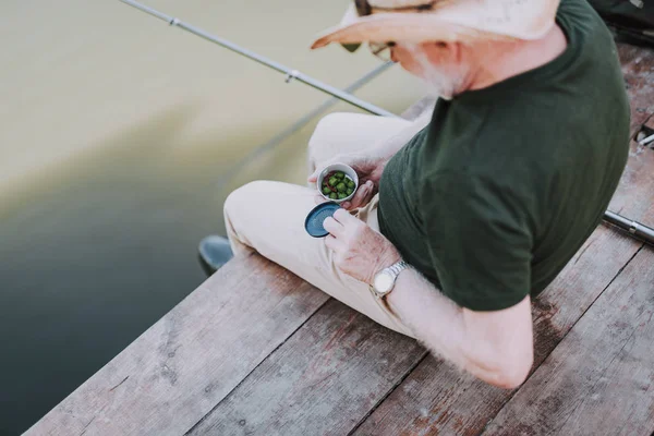 Vista superior de un anciano sosteniendo cebos para la pesca — Foto de Stock