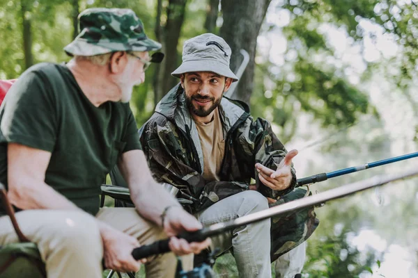 Agradable hombre hablando con su hijo mientras pesca — Foto de Stock