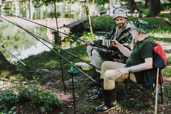 Veselá otec a syn loví společně na břehu řeky — Stock fotografie