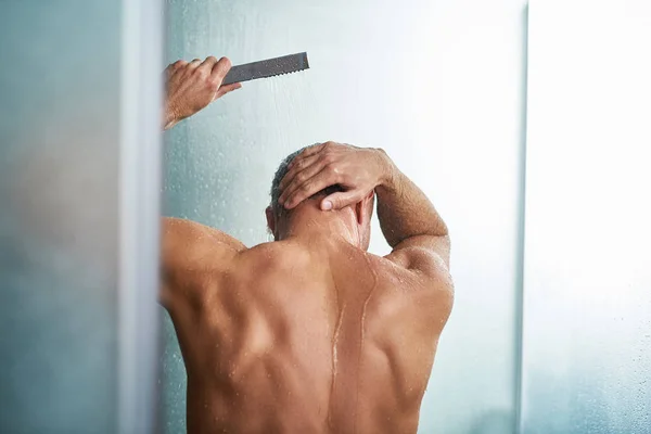 Jovem usando chuveiro enquanto se lava no banheiro — Fotografia de Stock