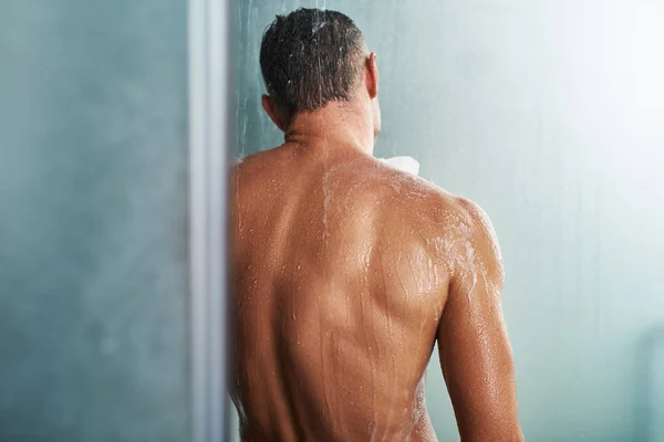 Knappe jongeman permanent onder waterdruppels en wassen zichzelf — Stockfoto