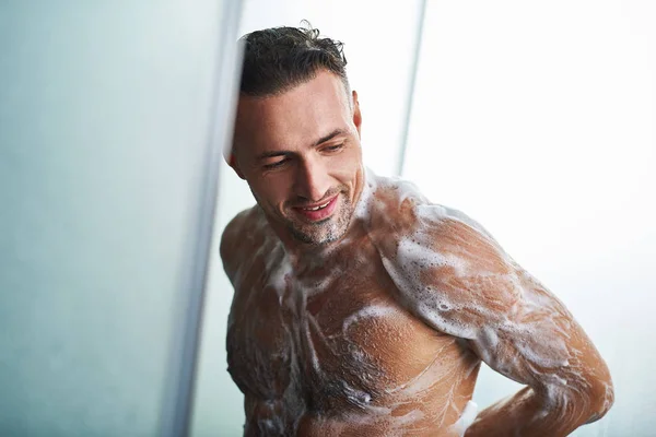 Joyeux jeune homme se lavant avec du gel douche — Photo