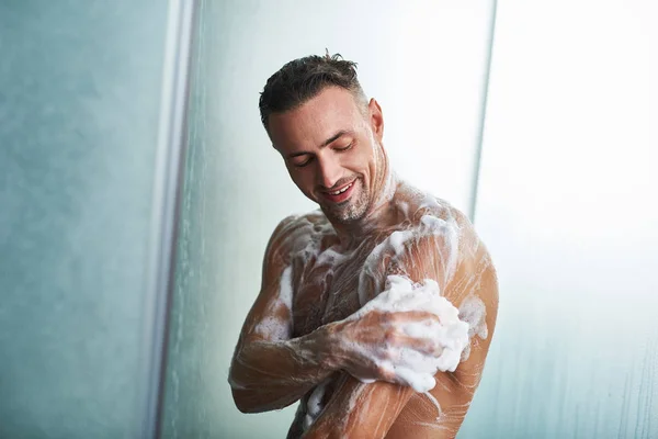 Knappe jongeman wassen zichzelf met douche gel — Stockfoto