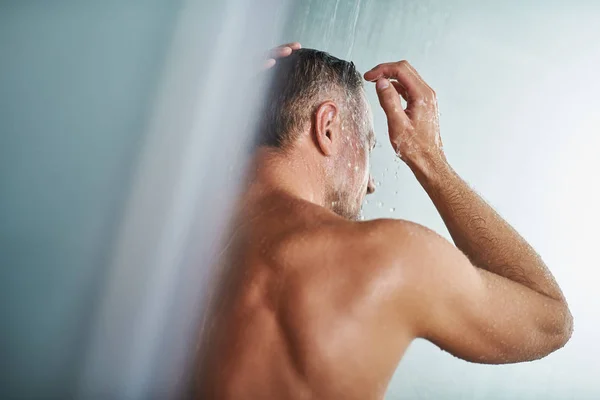 Jeune homme debout sous l'eau gouttes et se laver les cheveux — Photo