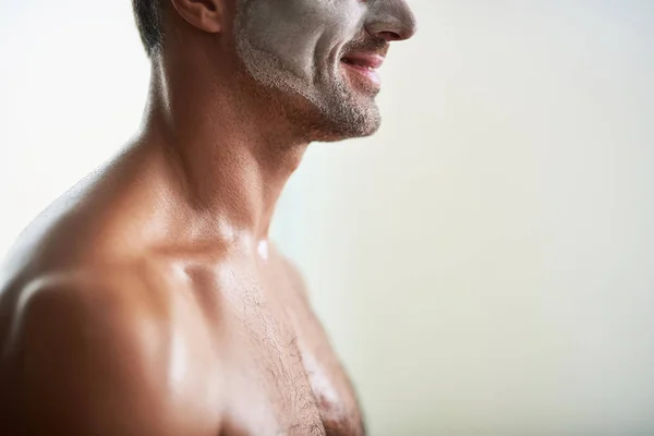 Νεαρός άνδρας με προσώπου καθαρισμού μάσκα στέκεται ενάντια σε λευκό φόντο — Φωτογραφία Αρχείου