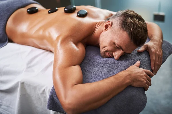 Jovem deitado na mesa de massagem enquanto tem tratamento de spa — Fotografia de Stock