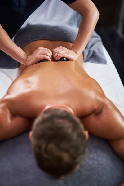 Ung man ligga på massagebänk under spa förfarandet — Stockfoto