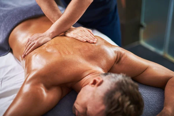 Mladý pán přijímá masáž zad na spa salon — Stock fotografie