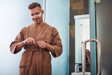 Çivi dosyası kullanarak gözlerinin altında yamalar ile genç adam