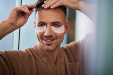 Saçları tarak ile fırçalama gözlerinin altında yamalar ile neşeli genç adam