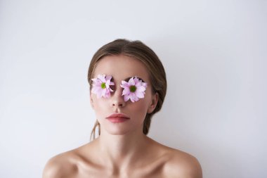 Gözleri beyaz arka plan üzerinde yalan üzerinde çiçeklerle çekici genç hanım