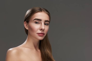 Çıplak omuz gri arka plan üzerinde duran ile çekici genç hanım