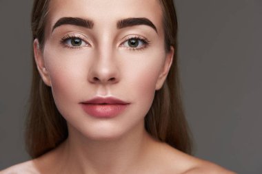 Gri arka plan üzerinde poz güzel genç kadın