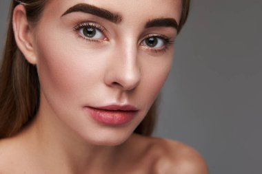 Doğal makyaj gri arka plan üzerinde izole çekici genç kadın