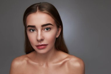 Gri arka planı poz çekici genç kadın