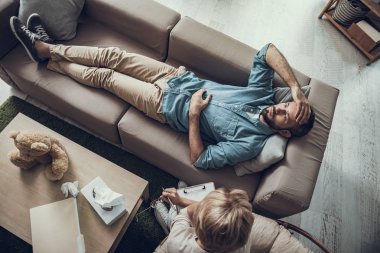 Adam kanepede yatan ve depresif görünümlü üstten görünüm