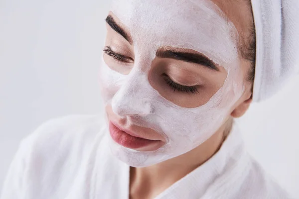 Menina bonita com máscara cosmética em seu rosto isolado no fundo branco — Fotografia de Stock