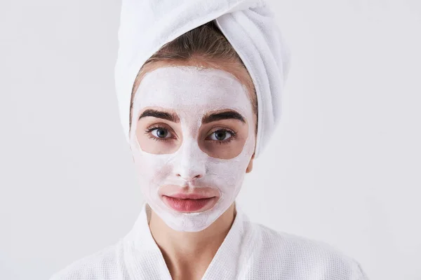 Ładna dziewczyna z oczyszczania maski na jej twarzy stały białym tle — Zdjęcie stockowe