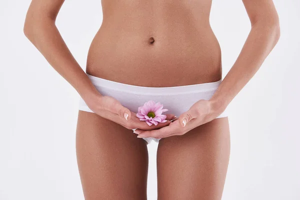 Young lady holding beautiful pink flower near underwear — Stock Photo, Image